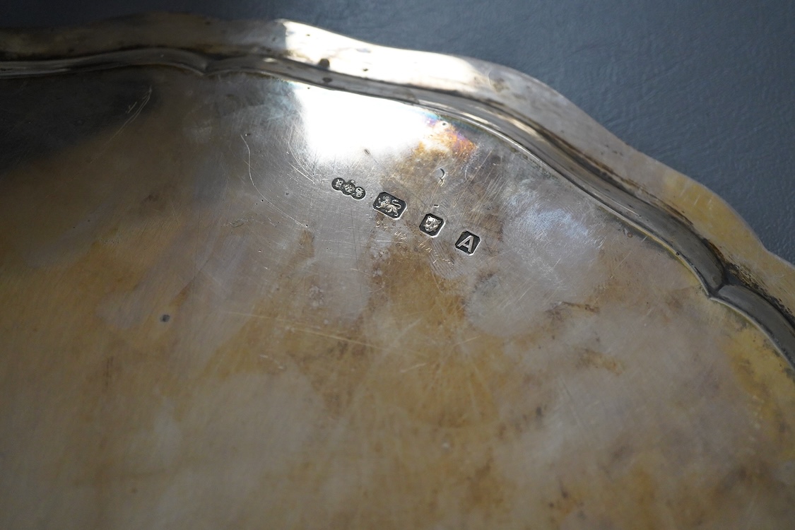 A George VI silver salver, of shaped circular form, on four claw and ball feet, with presentation inscription, Reid & Sons, London, 1936, 35.7cm, 40.5oz.